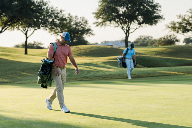 Two golfers in Juniper & James apparel walking up to the green