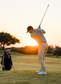 Golfer in pants and green polo hitting approach shot