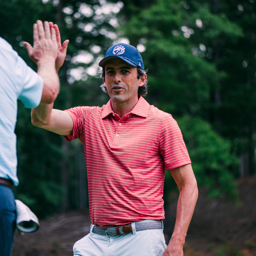Man in red striped shirt and blue cap giving a high-five outdoors