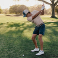 Person playing golf on a grassy course with trees in the background