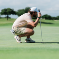 Golfer bending down to read a putt