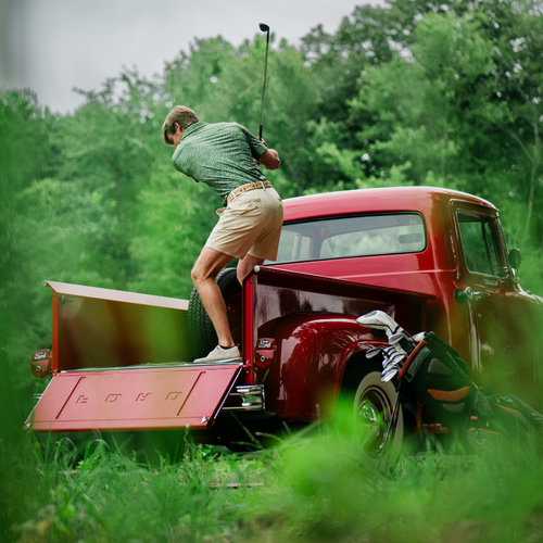 Man playing golf on the back of a red truck 